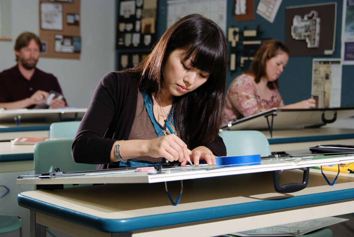 A student sitting at a desk working on a design.