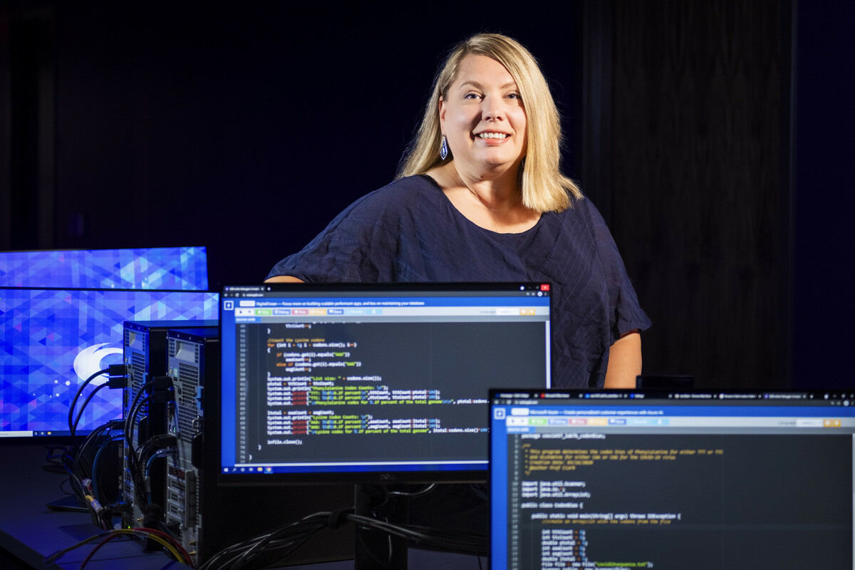Instructor standing next to computers with coding on the screens