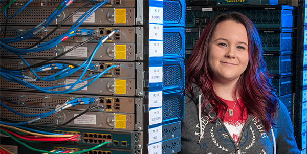 Student standing next to a computer network