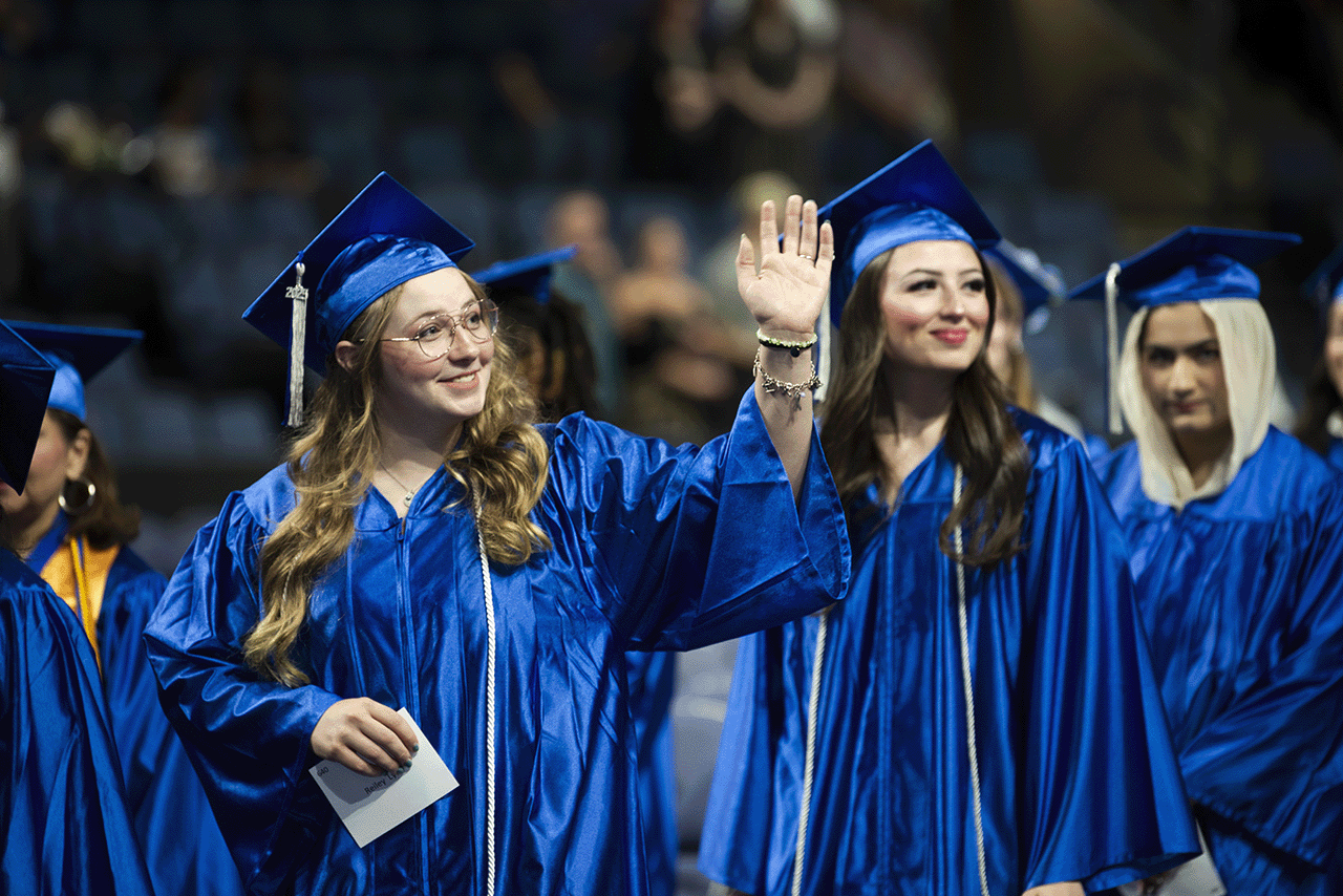 Students in a line at graduation holding their name cards