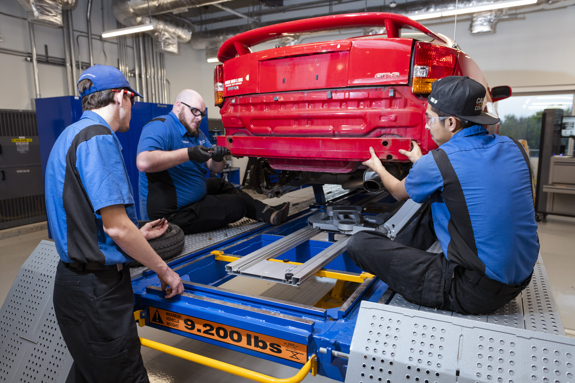 three technicians working on red car