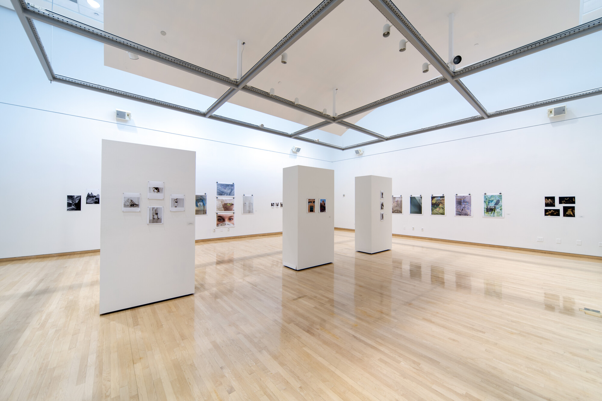 A photo of The Art Gallery at Collin College during a previous exhibition. Photos line the walls and adorn stands in the middle of the room. 