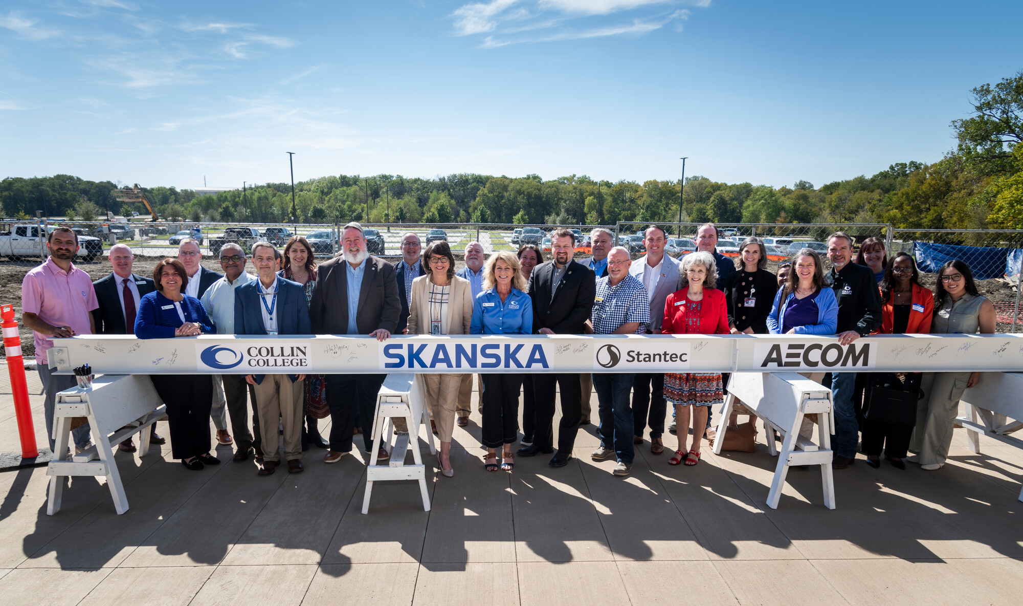 Group of people post in front of steel beam. 
