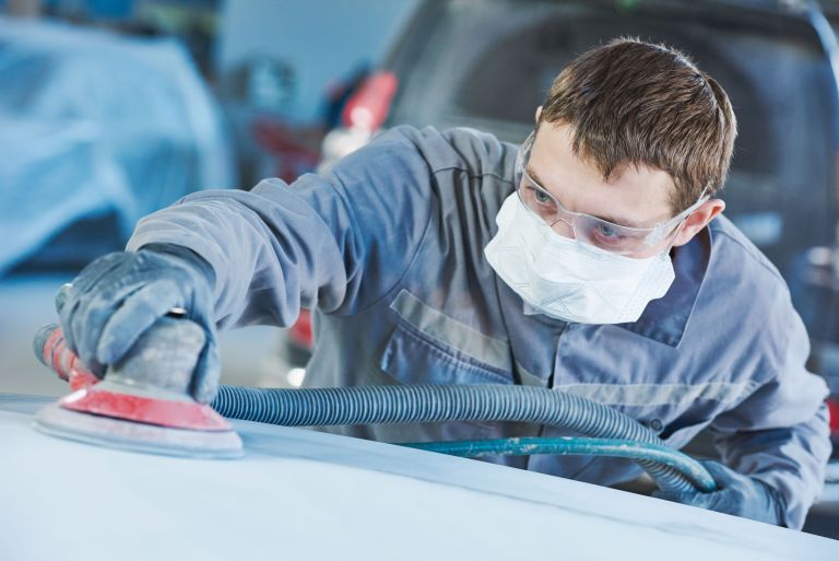 auto repairman grinding autobody bonnet